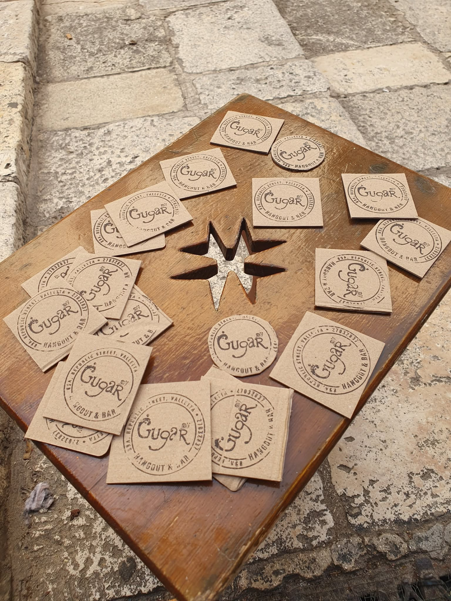 Hand-stamped Ġugar coasters on a wooden table